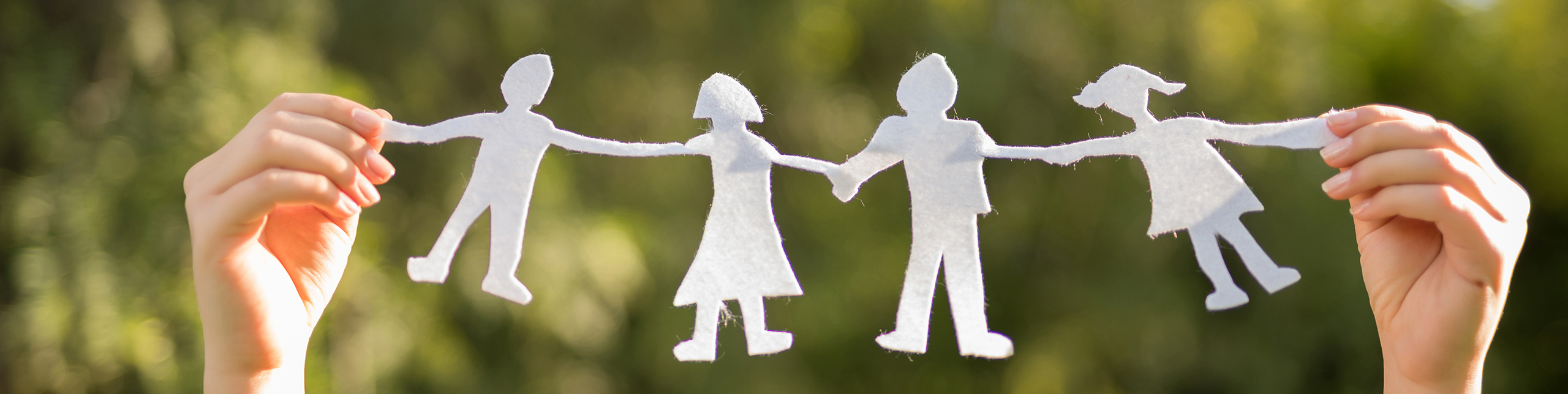 Hände halten Papierausschnitte von Menschen, die Vielfalt und Gemeinschaft symbolisieren.